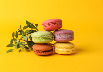 Set of colored macaroons on yellow background. French sweet delicacy.