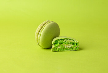 Green macaroon on green background. French sweet delicacy. Color trend