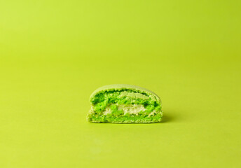 Half of french green macaroon on green background