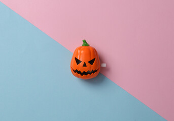Minimal halloween still life. Clockwork head of a jack o'lantern on a blue-pink background. Top view