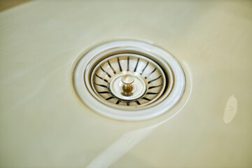 Close-up water drain down on stainless steel kitchen sink hole. Top view sewer in washbasin....