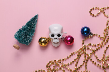 Skeleton skull with christmas decor on a pink background. Top view
