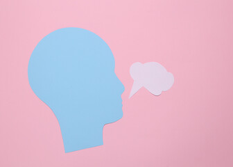 Paper cut human head with blank dialog cloud on pink background