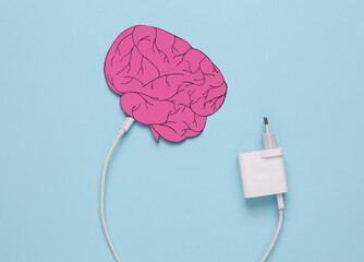 Recharge your brains. Paper-cut brain with a connected charger on a blue background
