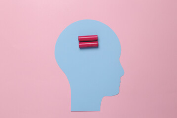 Energy boost for the brain. Paper cut human head with batteries on pink background