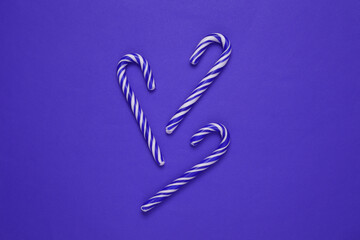 Christmas striped candy canes on purple background.
