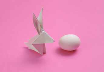 Origami easter bunny with egg on pink background