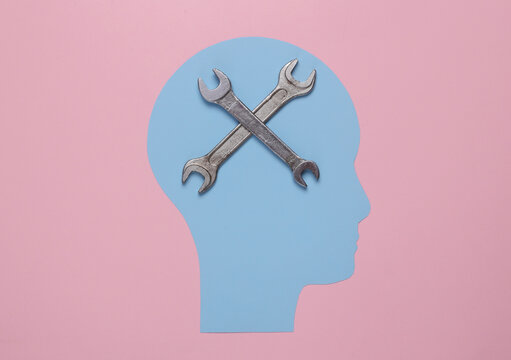 Paper-cut head and wrenches on pink background. Mental health, treatment