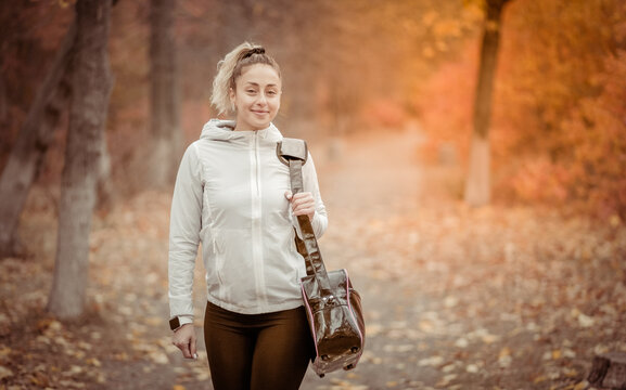 Attractive Sporty Woman With Bag Goes To Workout In Autumn Forest Or Park