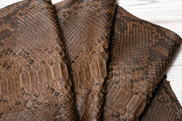 Brown dyed folded natural genuine python leather on the wooden table	