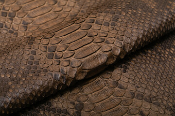 Brown dyed folded natural genuine python leather on the wooden table	