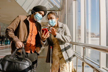 Indian couple wearing face masks using mobile phone in airport