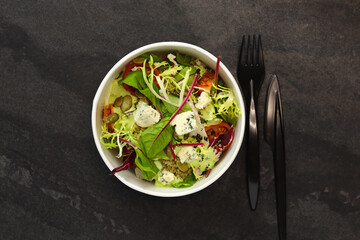 Healthy salad with beetroot, blue cheese, tomatoes, quinoa and pumpkin seeds in eco paper package for take away or food delivery isolated on black background. Top view. Keto diet.
