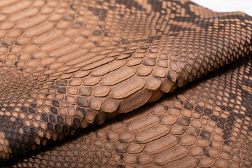 Naklejka premium beige spotted dyed genuine natural python leather on the wooden table 