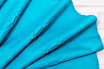 blue dyed genuine natural python leather on the wooden table
