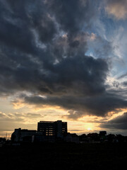 Sunset over the city. Old construction industrial area. Blue and yellow sky with dark clouds before the rain