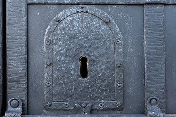 Keyhole in an old iron door for a large key. There are traces of forging on the black surface. Background. Texture. Concept.