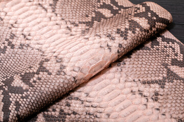 pink spotted dyed genuine natural python leather on the wooden table	
