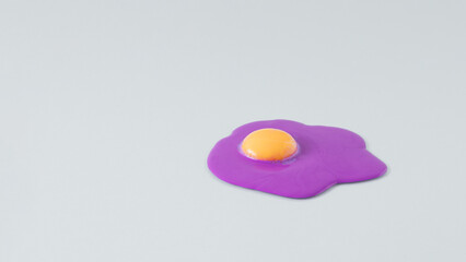 Creative arrangement made of vivid purple colored egg white and egg yolk on a gray background. Minimal broken egg concept.