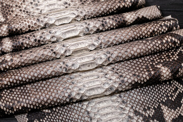grey spotted dyed folded natural genuine python leather on the wooden table	

