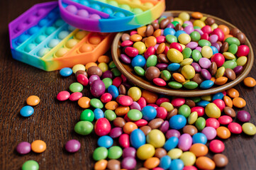 Fototapeta na wymiar Many tasty little colored candies and pip it on wooden background