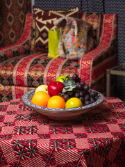 Apples, oranges and grapes in a plate on the table