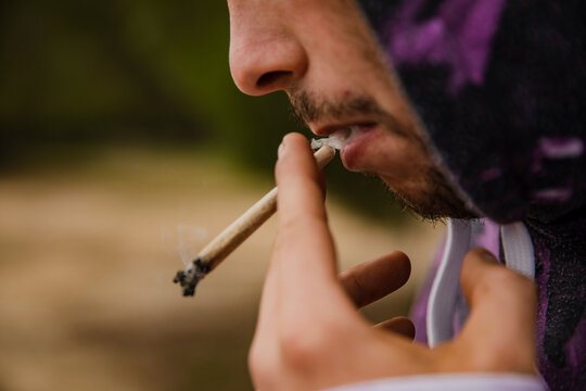 Mouth of a boy with a lighted marijuana cigarette. Close-up