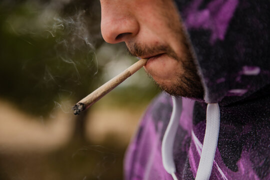 Mouth of a boy with a lighted marijuana cigarette. Close-up