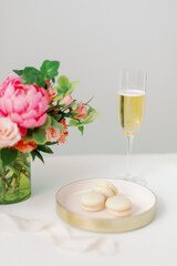 pink and peach flowers and vanilla macarons with glass of champagne