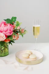 Wall murals Macarons pink and peach flowers and vanilla macarons with glass of champagne
