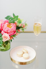 pink and peach flowers and vanilla macarons with glass of champagne