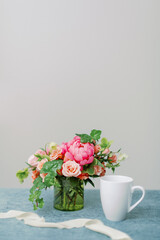 Obraz na płótnie Canvas pink and peach flower centerpiece with white coffee mug