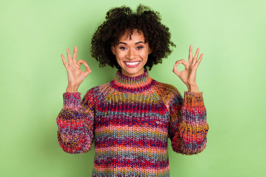 Photo of impressed young valume hairdo lady show okey wear colorful pullover isolated on green color background