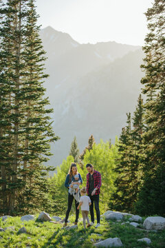 Family in nature playing with child and baby with trees and moun