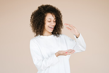 Young African american girl wearing over brown background gesturing with hands showing big and large size sign, measure symbol. Smiling looking at the camera. Measuring      