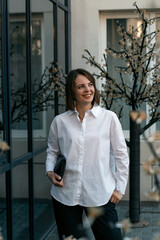 Portrait of successful young woman in white shirt and black trousers. Business woman in semi-casual.