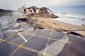 Devastation concept. Waves of high tide created by a tsunami destroys houses located on the coast,...