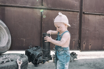 one year old baby playing mechanic among auto parts