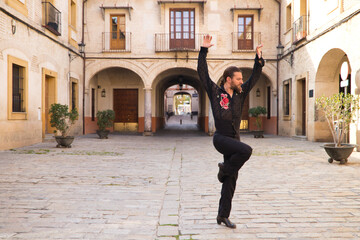 middle-aged flamenco man with long hair dancing flamenco in a square with columns and balconies in seville, spain. Feel the passion. Flamenco dance concept cultural heritage of humanity.