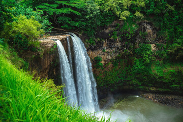 The stunning and beautiful Wailua Falls on the Hawaiian island of Kauai surrounded by lush tropical plants and greenery