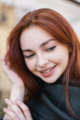 Fototapeta premium portrait of young redhead woman in headscarf smiling while looking down.