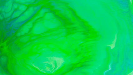 Fototapeta na wymiar Fluid art background in green color. Green-turquoise stains on liquid. Creative background with blurred paints. Background for an eco-friendly concept