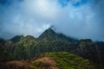 Fototapeta na wymiar The gorgeous rugged wilderness and cliffs of Kauai's Napali Coast in Hawaii, with low clouds and mist hanging over the mountain peaks under a stormy grey sky