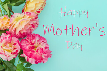 Happy Mother's Day lettering with pink roses on blue background with selective focus