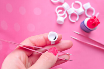 White ring holders for drop of glue for eyelash extensions on pink background 
