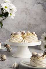 Elegant meringue servings with quail egg toppings presented on white plates and stand.