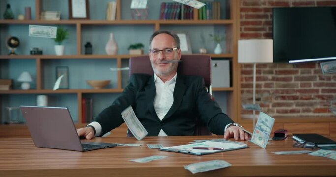 Happy bearded businessman enjoy with money rain while working in office. Mature Male feeling fun after completed work project receiving dollars. Business concept.