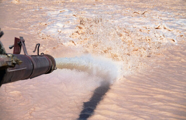 Foamy muddy water gushes out of the pipe under high pressure. Discharge of excess water from a...