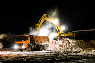 Excavator loading sand into truck at sand quarry. Long exposure