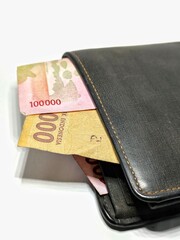 Money in black leather wallet isolated on white background